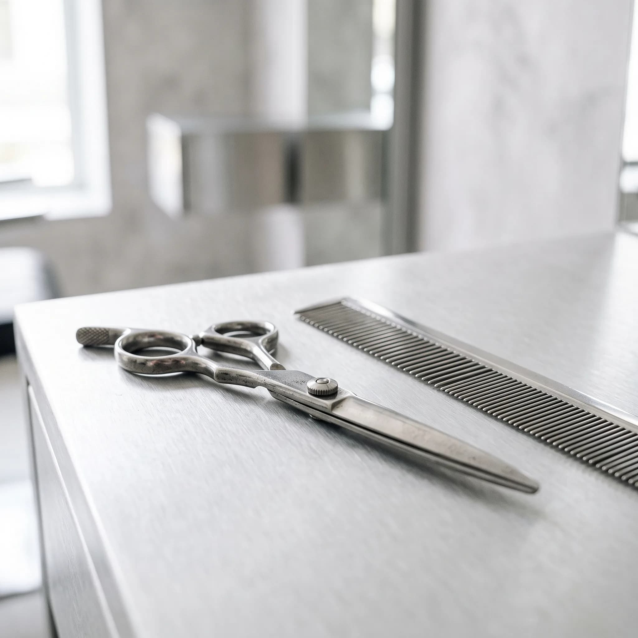 Barbierschere und Kamm auf gebürstetem Aluminium