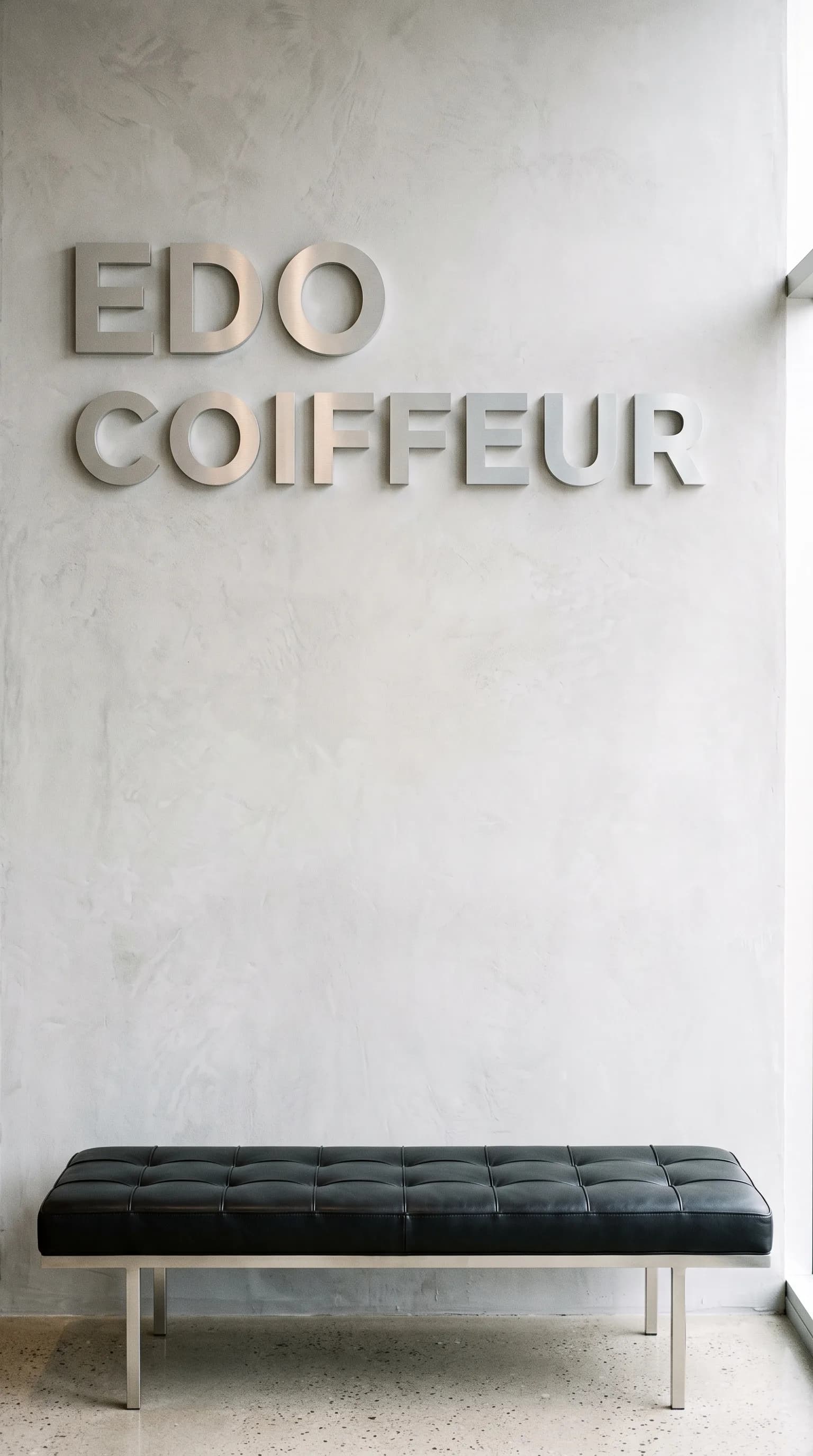Eingangsbereich in Basel mit dem Schriftzug Edo Coiffeur auf grauer Wand